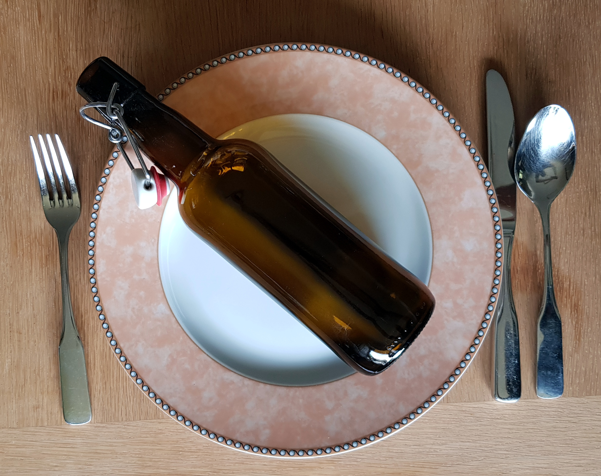 Kalorien, kcal und kJ - Nhrwertangaben. Bierflasche auf leerem Teller mit Besteck