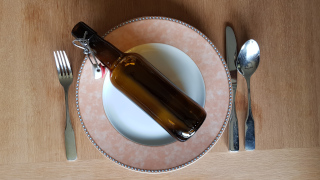 Kalorien, kcal und kJ - Nhrwertangaben. Bierflasche auf leerem Teller mit Besteck